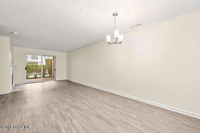 a view of empty room with wooden floor and window