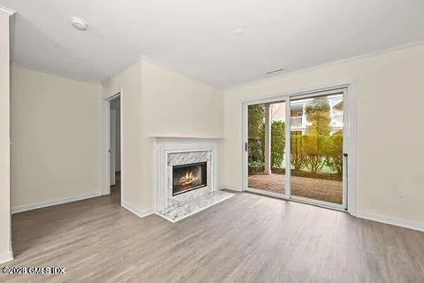 an empty room with wooden floor fireplace and windows