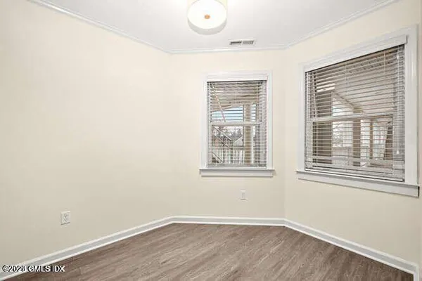 an empty room with wooden floor and windows