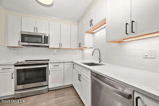 a kitchen with white cabinets stainless steel appliances and sink