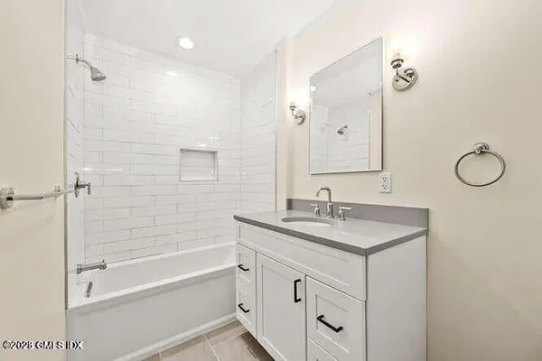 a bathroom with a granite countertop sink a mirror a vanity and a bathtub