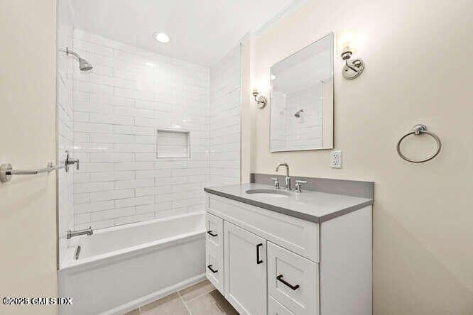 51 Forest Avenue, Unit 147 Old Greenwich, CT 06870 - Photo 9 of 19 a bathroom with a granite countertop sink a mirror a vanity and a bathtub