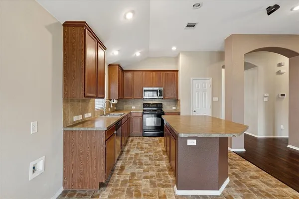 a large kitchen with stainless steel appliances granite countertop a stove refrigerator and a sink