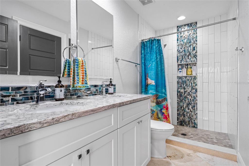 1451 Lyndale Boulevard Winter Park, FL 32789 - Photo 78 of 89 a bathroom with a granite countertop sink a toilet a mirror a vanity and shower