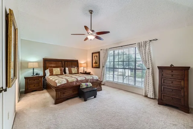 a spacious bedroom with a bed a dresser and a chandelier