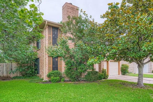 a front view of a house with a garden and tree