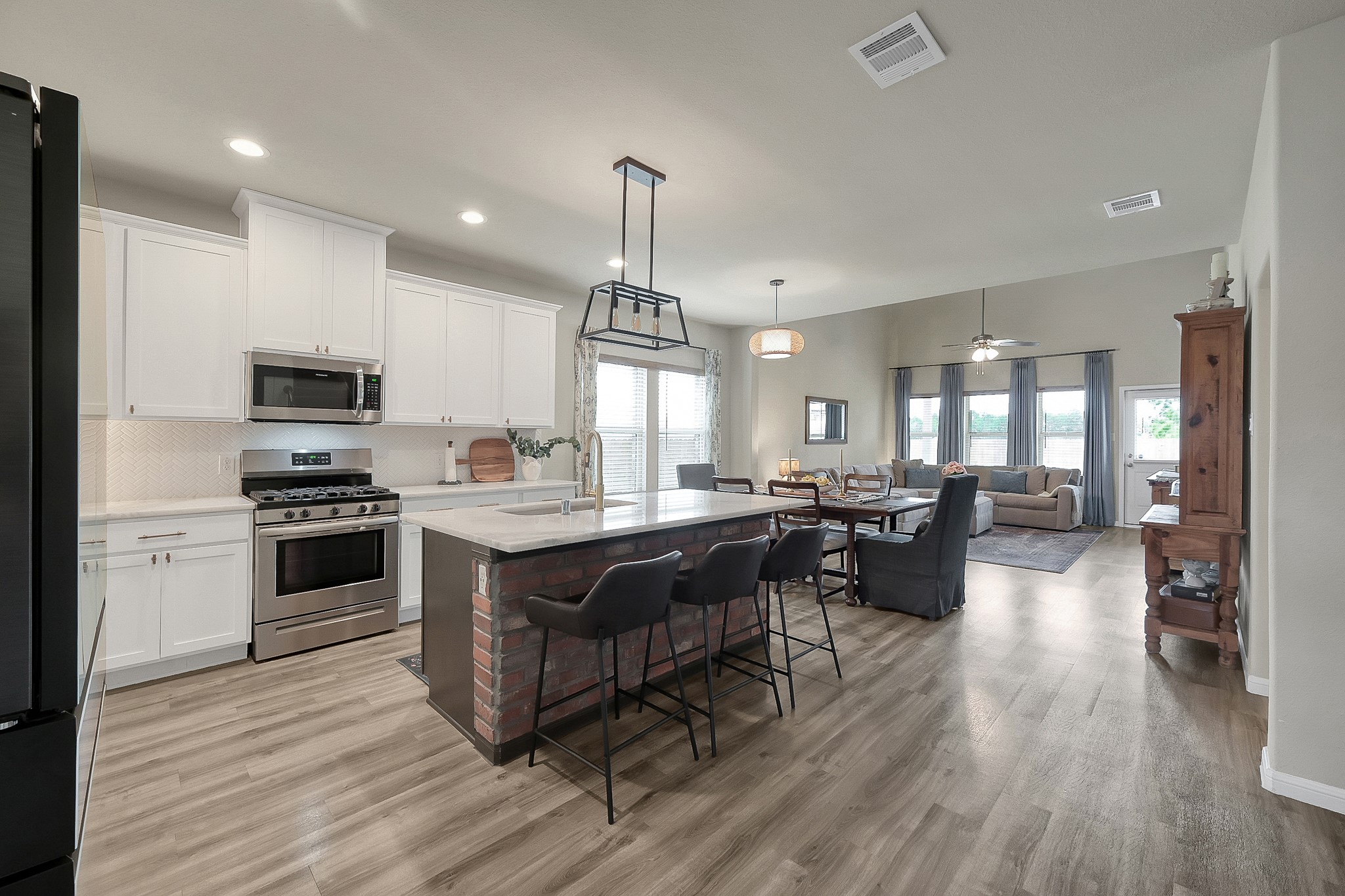 679 Red Elm Lane Conroe, TX 77304 - Photo 9 of 45 a kitchen with a stove a sink dishwasher a refrigerator and a dining table with wooden floor