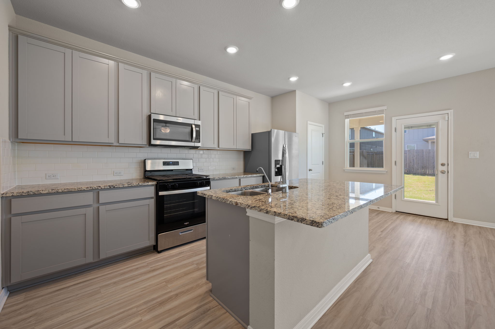 529 View Drive Georgetown, TX 78628 - Photo 6 of 20 Kitchen with gray cabinetry, stainless steel appliances, light stone counters, backsplash, and light wood-style floors