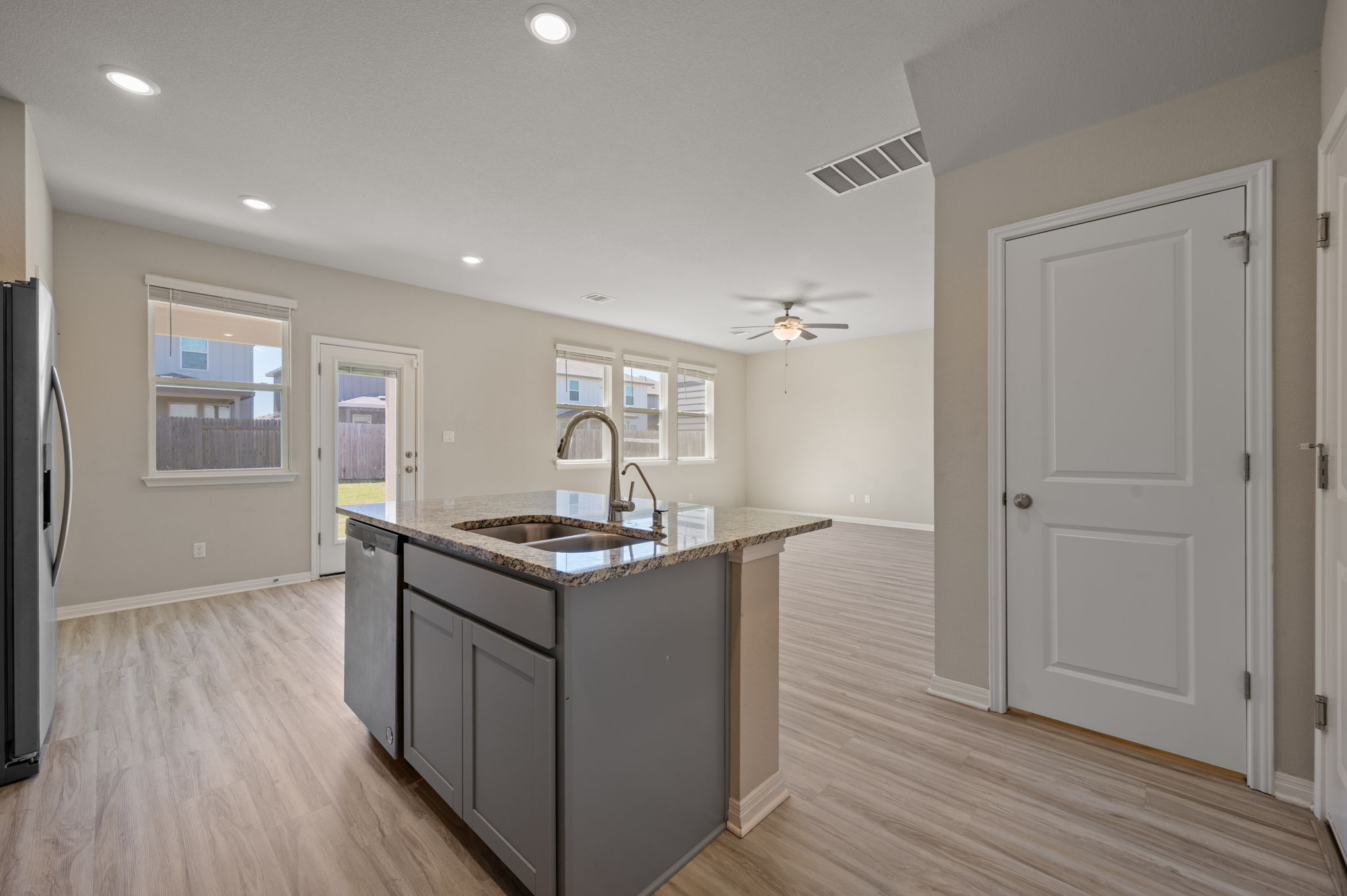 529 View Drive Georgetown, TX 78628 - Photo 7 of 20 Kitchen with a kitchen island with sink, light stone counters, light wood-style floors, stainless steel appliances, and ceiling fan