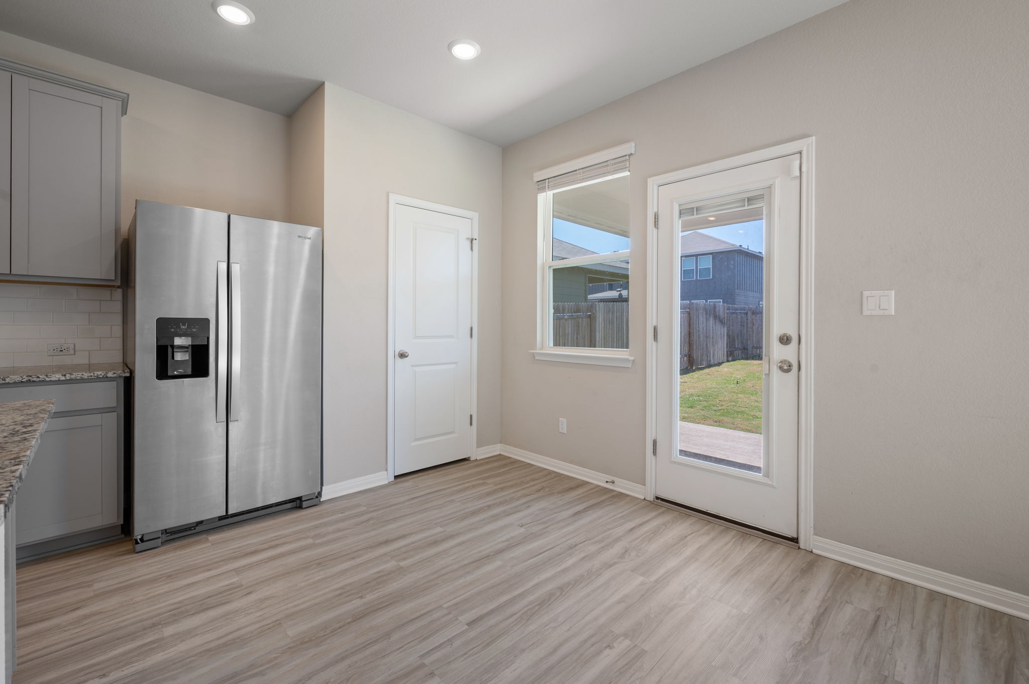 529 View Drive Georgetown, TX 78628 - Photo 8 of 20 Kitchen featuring gray cabinetry, stainless steel refrigerator with ice dispenser, light stone countertops, light wood-style floors, and backsplash