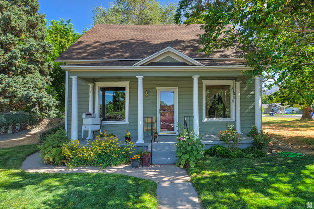 178 17th Street Ogden, UT 84404 - Photo 2 of 29 Green exterior with white trim featuring a covered porch with white columns, a dark shingle roof, and a mature tree providing shade
