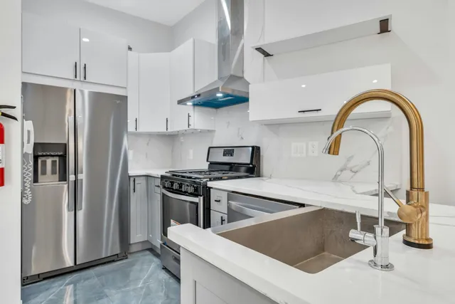 a kitchen with stainless steel appliances granite countertop a sink a stove and a refrigerator