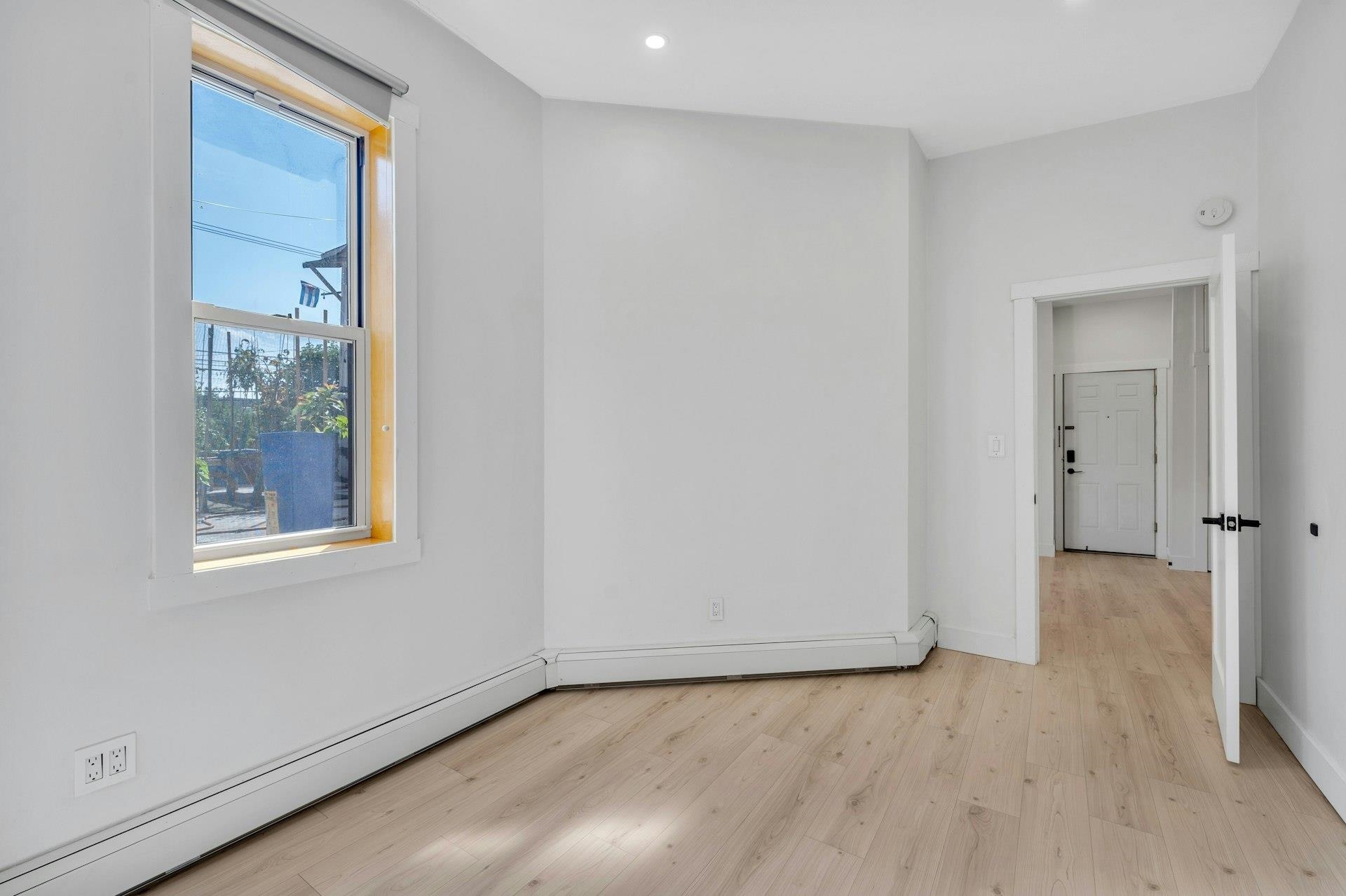 202 48th Street, Unit 3 Union City, NJ 07087 - Photo 9 of 17 a view of an empty room with wooden floor and a window