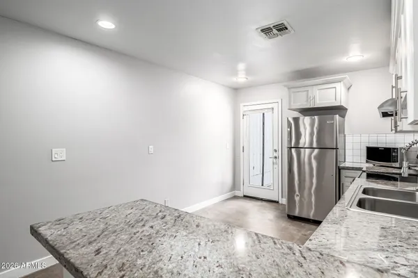 a kitchen with granite countertop white cabinets and stainless steel appliances