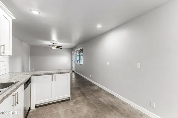 an empty room with ceiling fan and windows