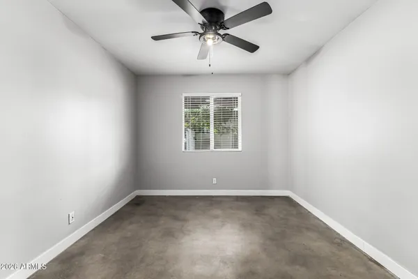 an empty room with chandelier fan and windows