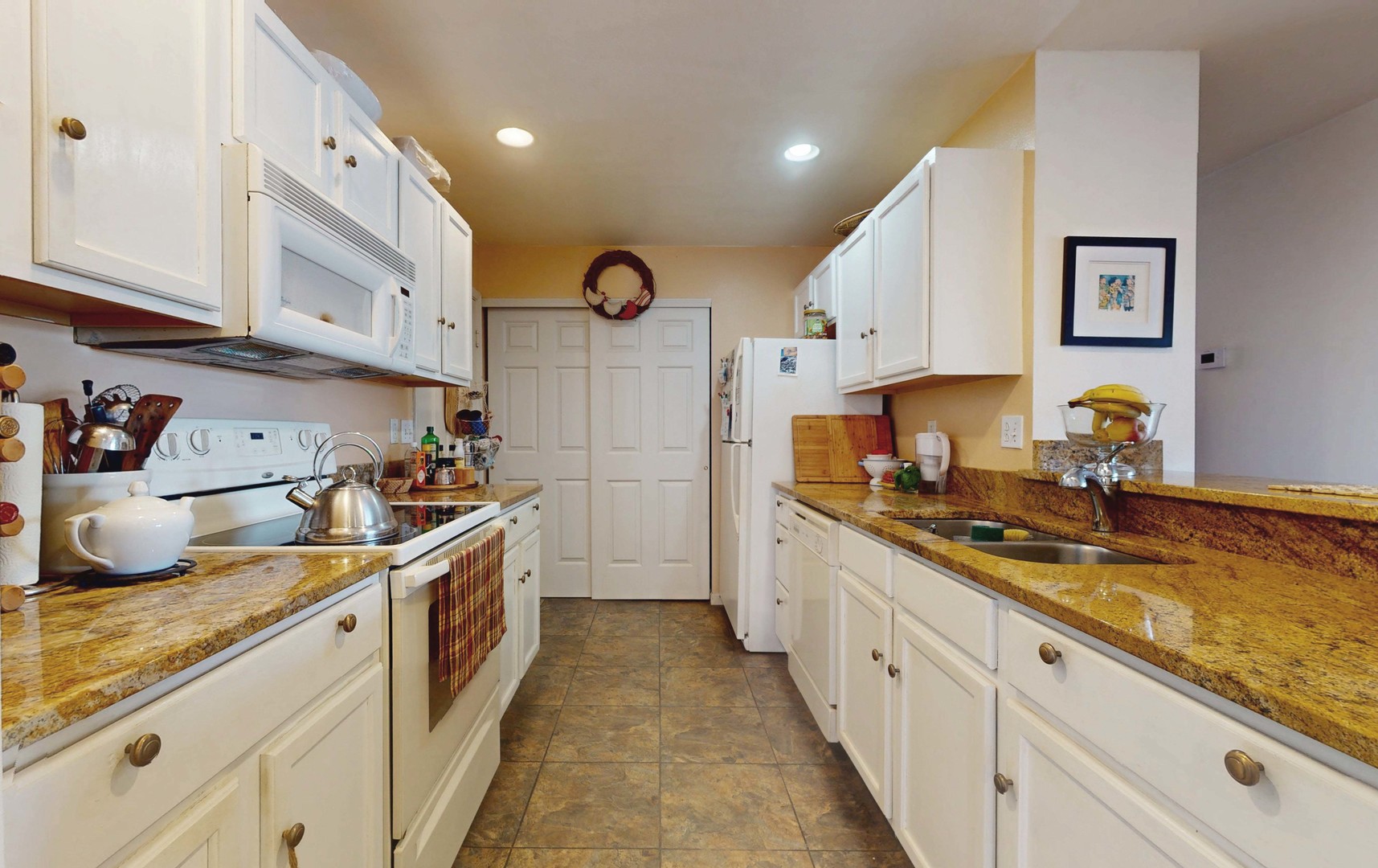 2408 Windward Boulevard, Unit 106 Champaign, IL 61821 - Photo 4 of 17 a white kitchen with stainless steel appliances granite countertop a sink and cabinets