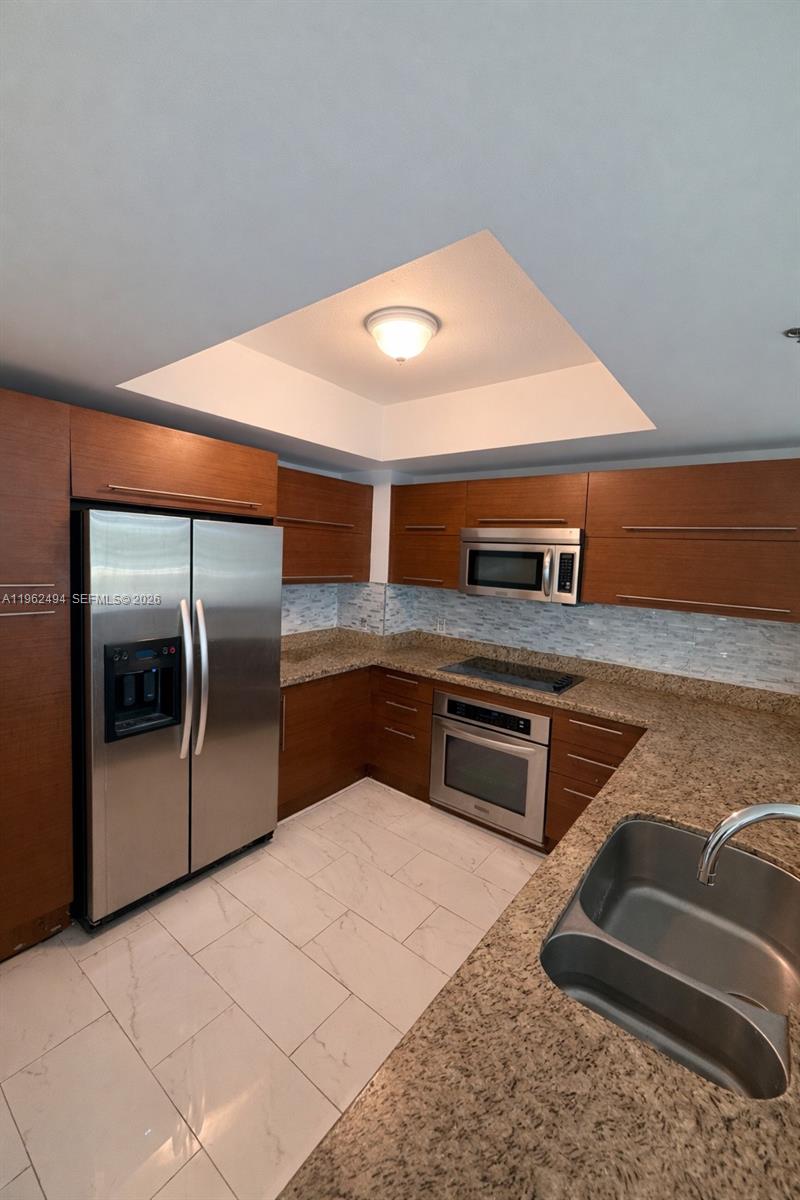 2641 North Flamingo Road, Unit TH5N Sunrise, FL 33323 - Photo 11 of 12 a kitchen with stainless steel appliances granite countertop a sink and a stove