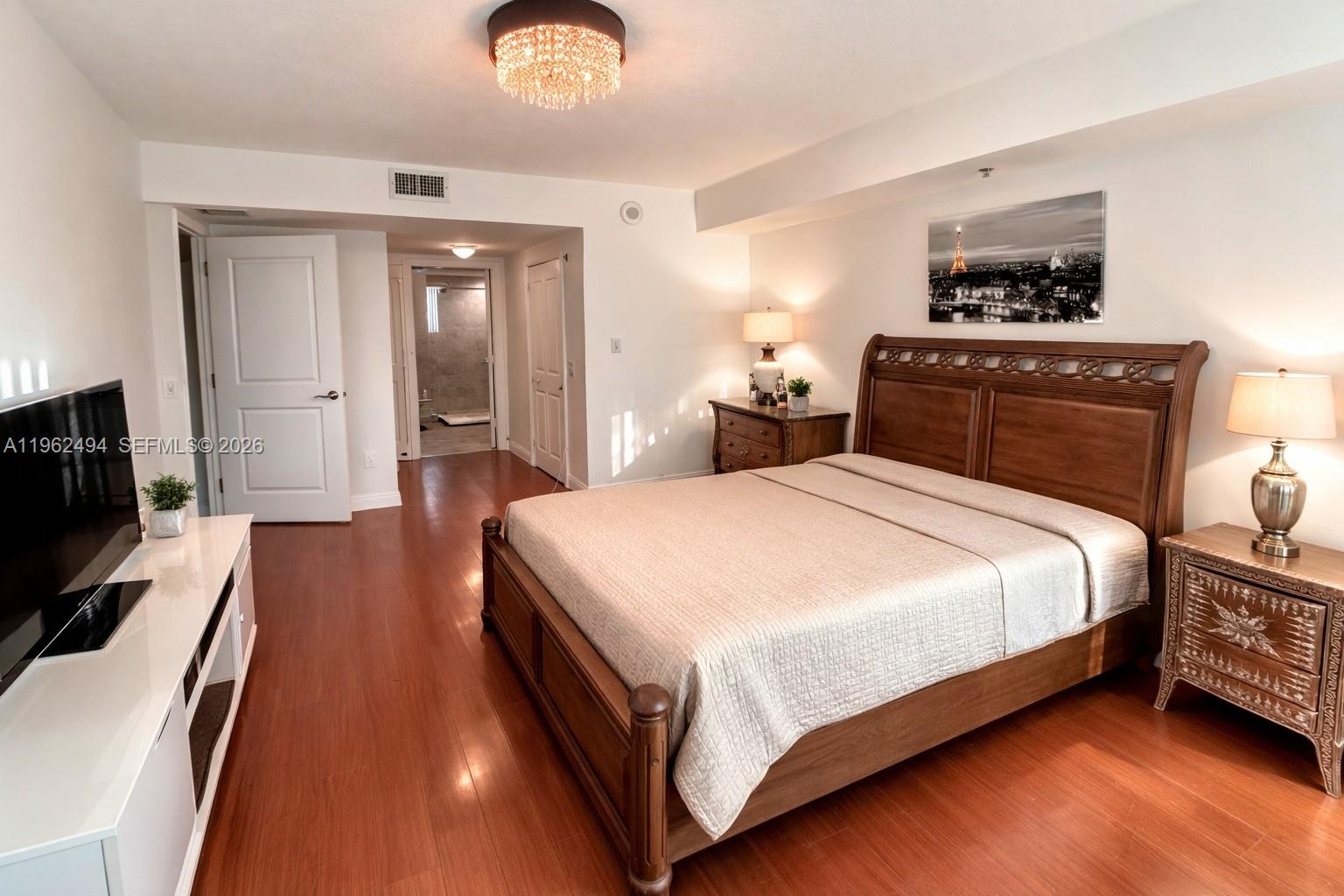 2641 North Flamingo Road, Unit TH5N Sunrise, FL 33323 - Photo 5 of 12 a spacious bedroom with a bed and a flat screen tv