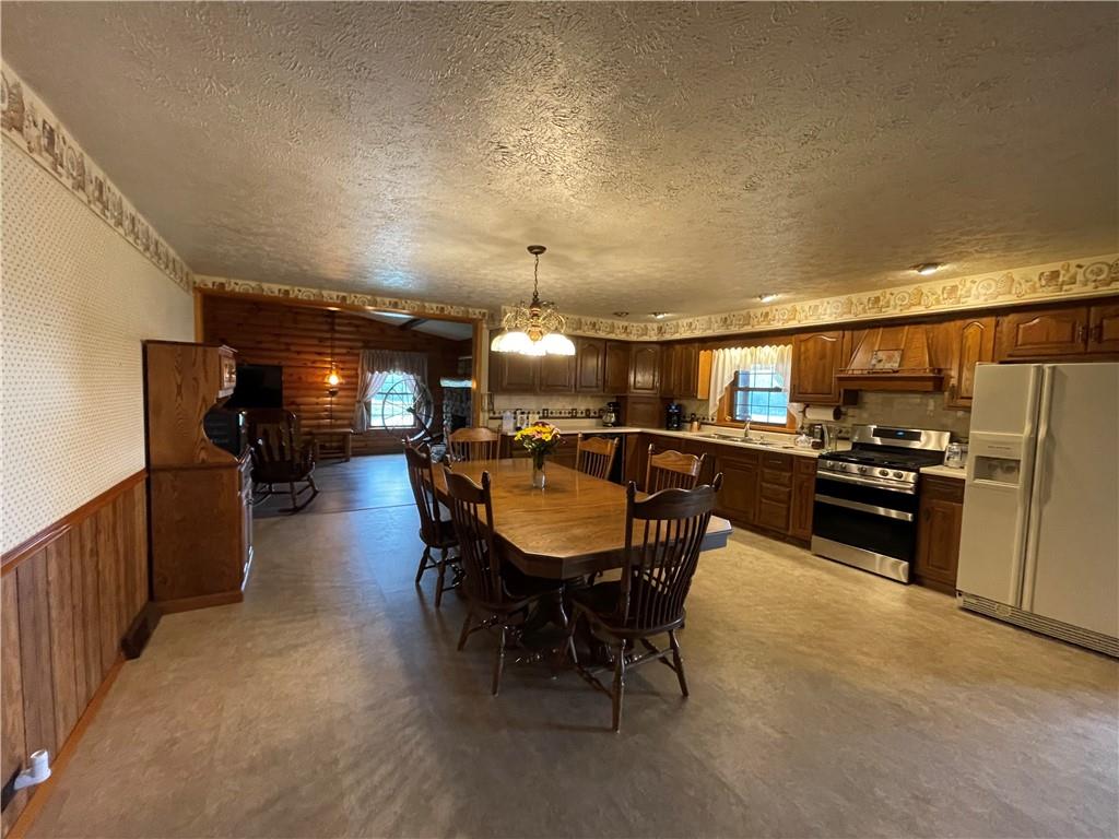 1844-1846 Cherry Tree Road Cherry Tree, PA 15724 - Photo 3 of 26 a kitchen with stainless steel appliances kitchen island granite countertop a refrigerator a sink a stove and a dining table with wooden floor