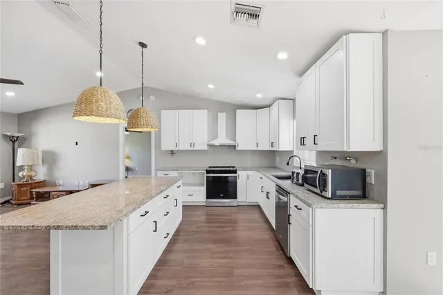 a large kitchen with stainless steel appliances kitchen island a large counter top a stove a sink and a refrigerator