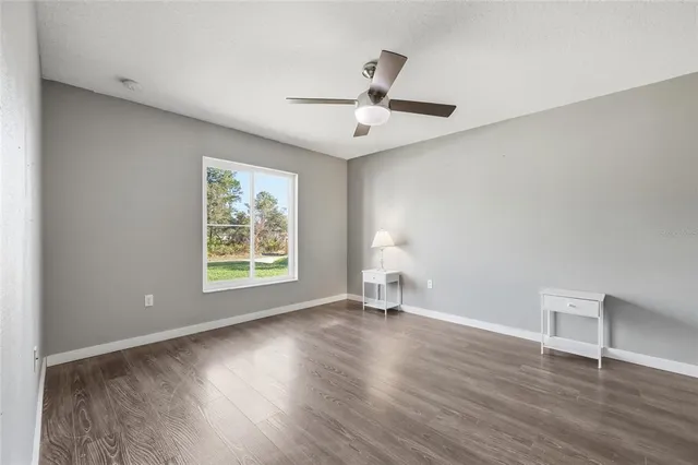a view of an empty room with a window and wooden floor