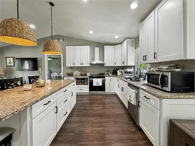a large kitchen with granite countertop a stove top oven a sink a counter space and cabinets