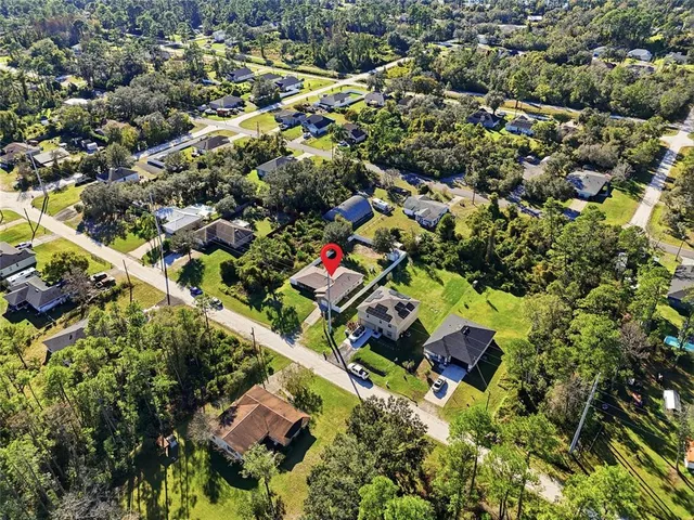 an aerial view of residential houses with outdoor space and trees
