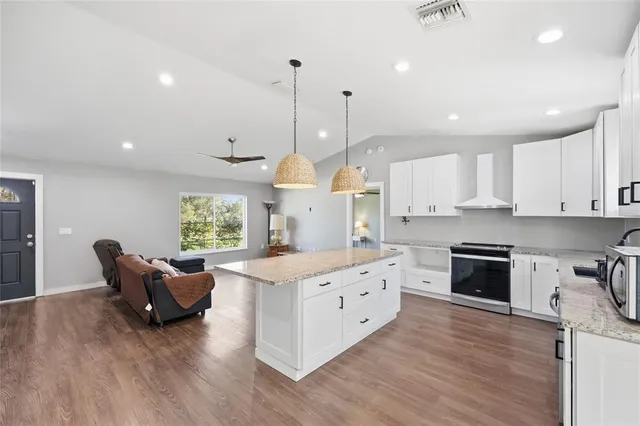 a large kitchen with stainless steel appliances granite countertop a stove and a wooden floors