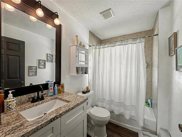 a bathroom with a granite countertop sink toilet mirror and a bathtub