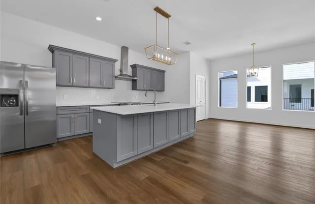 a kitchen with stainless steel appliances granite countertop a refrigerator a sink dishwasher a stove and a wooden floors