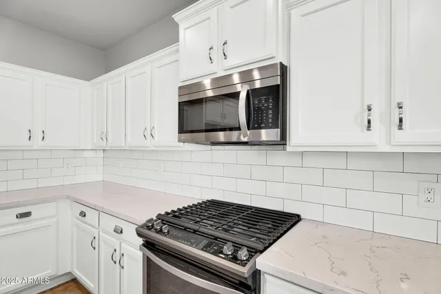 a kitchen with a sink a stove a refrigerator and white cabinets