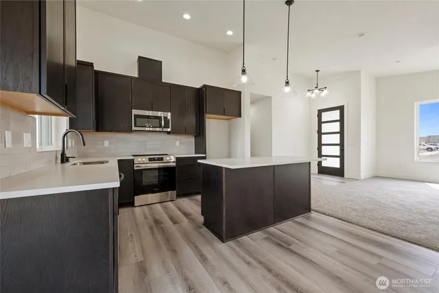 a large kitchen with stainless steel appliances a large counter top a stove and a sink