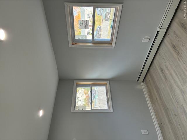 56 Ash Street Central Islip, NY 11722 - Photo 10 of 14 Unfurnished room featuring a baseboard heating unit, recessed lighting, light wood-type flooring, and healthy amount of natural light