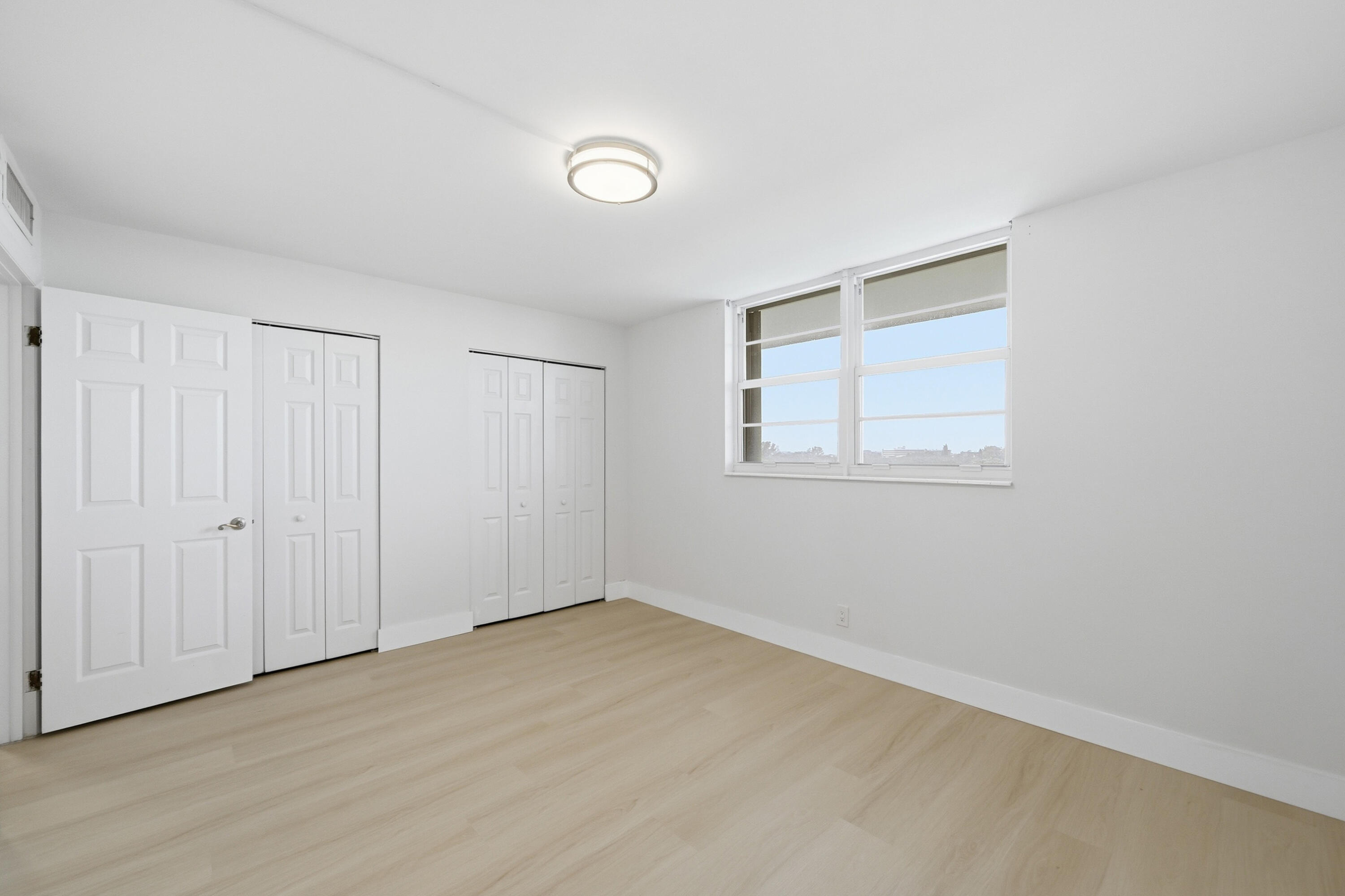 5700 Northwest 2nd Avenue, Unit 604 Boca Raton, FL 33487 - Photo 15 of 43 a view of an empty room with wooden floor and a window
