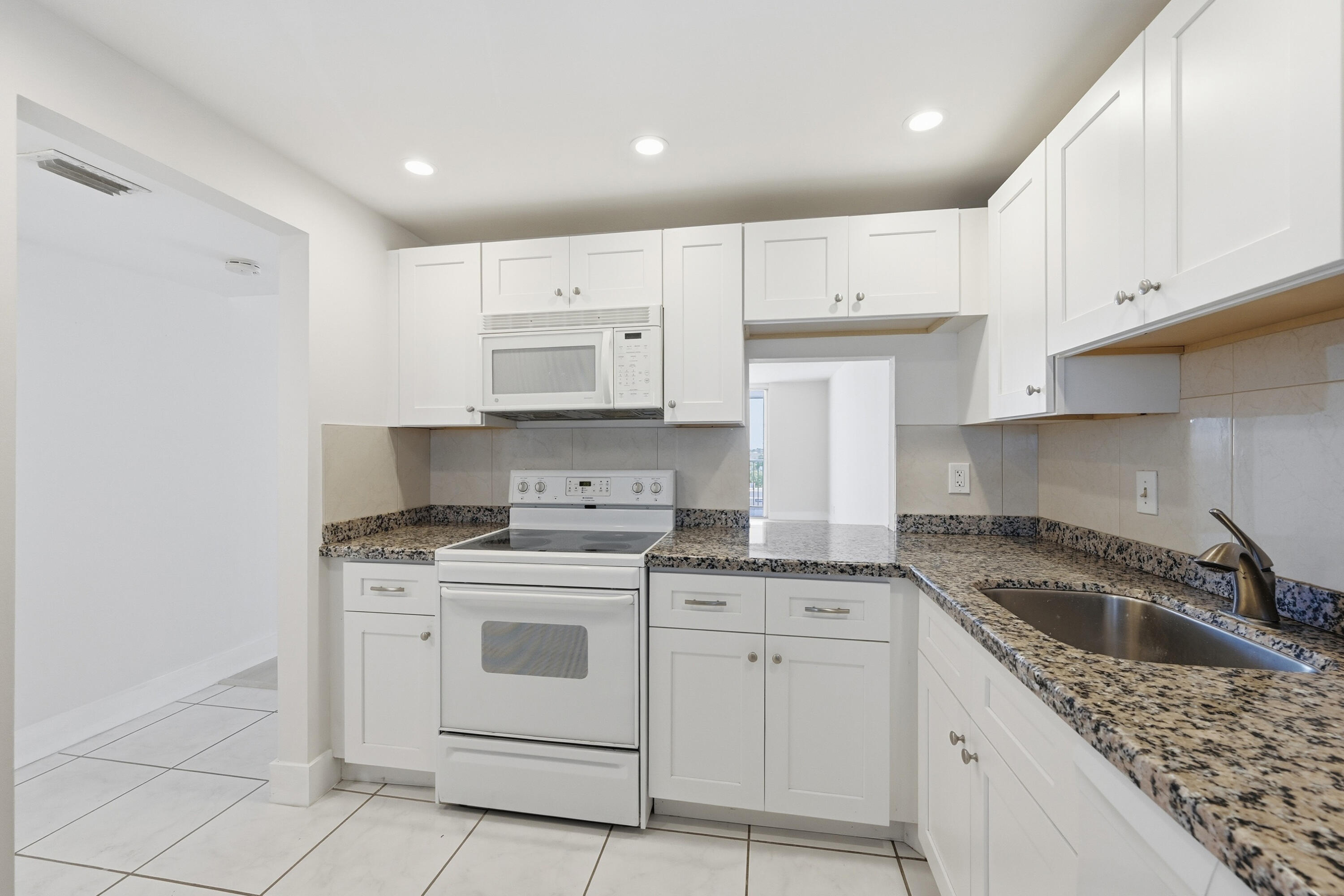5700 Northwest 2nd Avenue, Unit 604 Boca Raton, FL 33487 - Photo 6 of 43 a kitchen with granite countertop white cabinets and white appliances