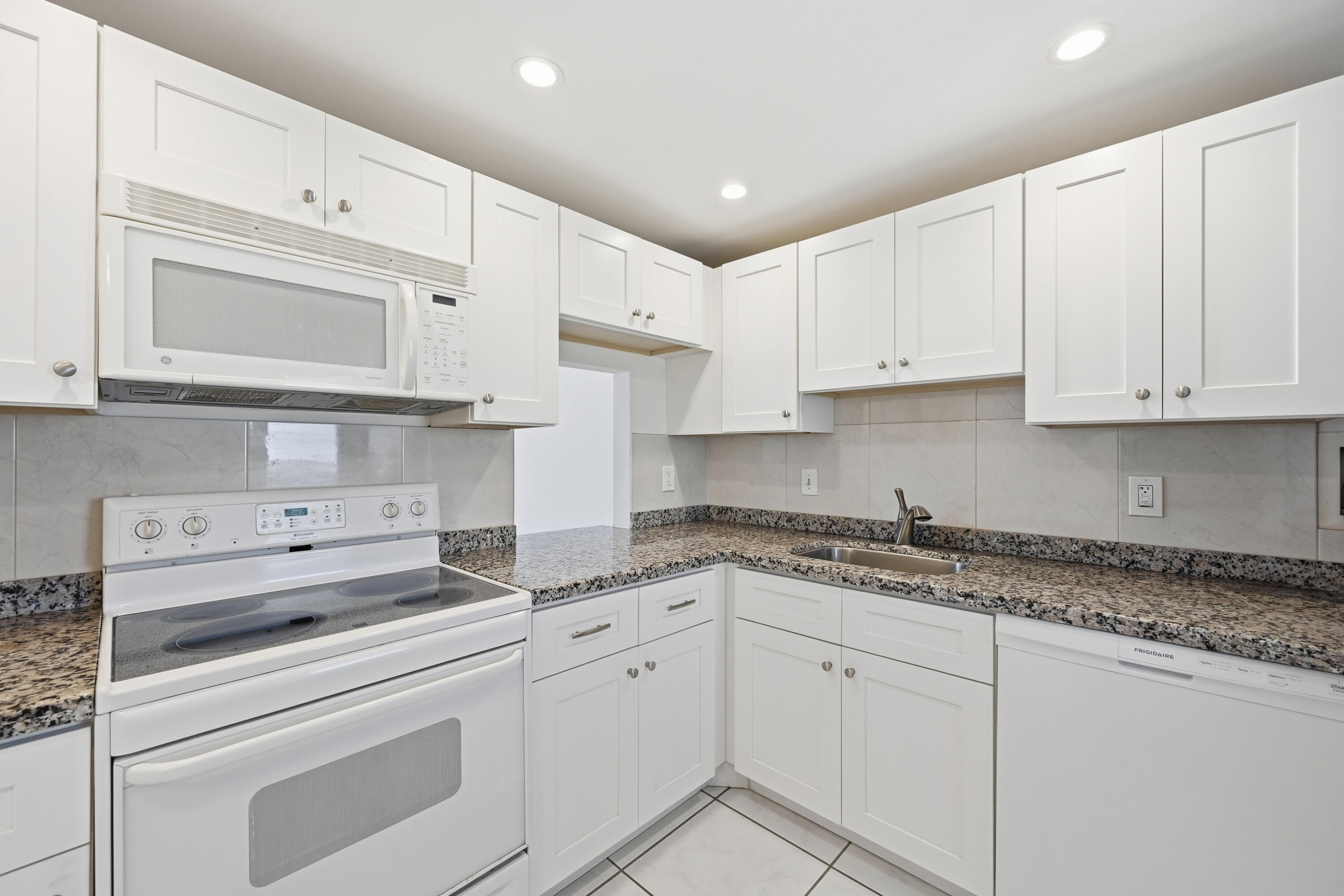 5700 Northwest 2nd Avenue, Unit 604 Boca Raton, FL 33487 - Photo 7 of 43 a kitchen with granite countertop white cabinets white appliances and granite counter tops