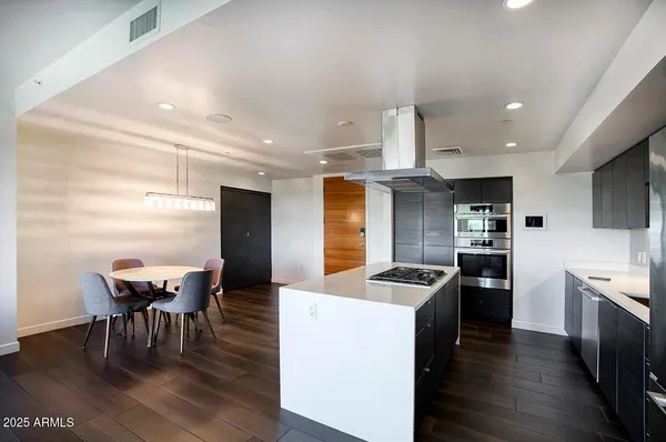 a kitchen with granite countertop kitchen island stainless steel appliances a dining table and chairs