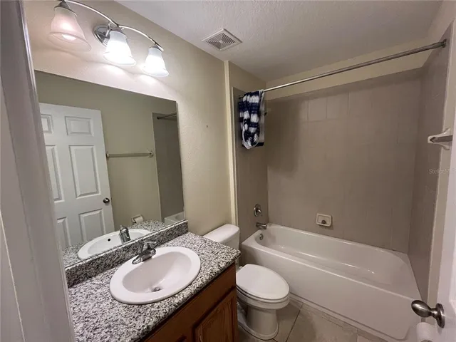 a bathroom with a granite countertop sink toilet a mirror and shower