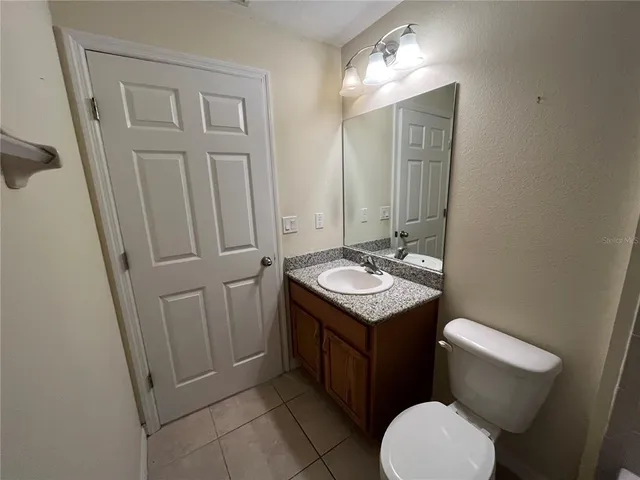 a bathroom with a granite countertop toilet sink and mirror