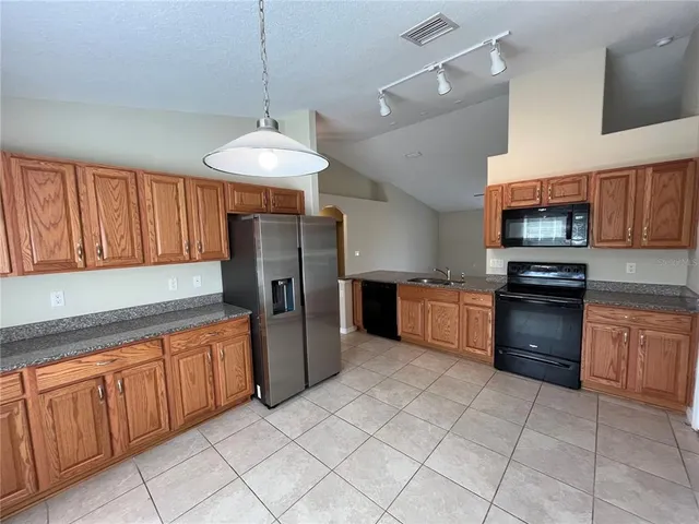 a kitchen with stainless steel appliances granite countertop a refrigerator oven a sink dishwasher and a stove