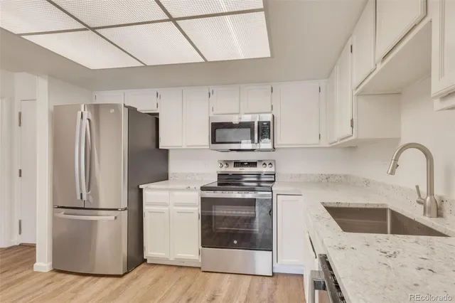 a kitchen with granite countertop white cabinets and stainless steel appliances