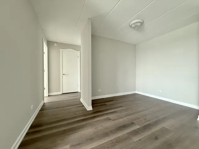 a view of an empty room with wooden floor