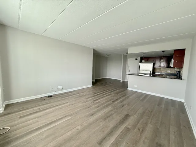 a view of a kitchen and an empty room with wooden floor