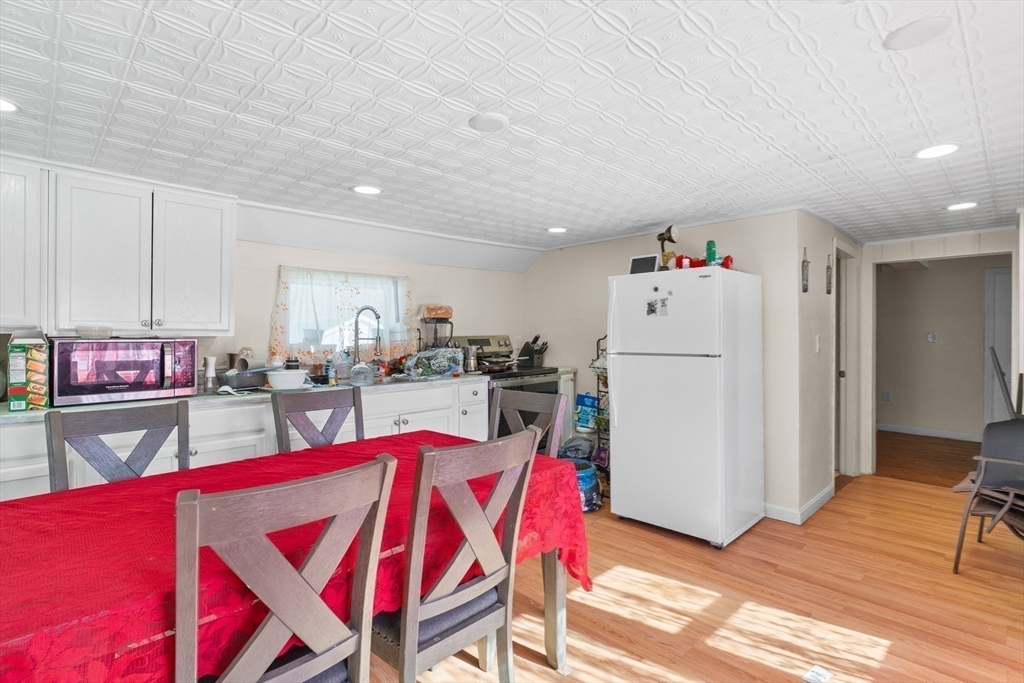 192 East Spring Street Avon, MA 02322 - Photo 20 of 25 a living room with furniture a kitchen island with furniture a refrigerator and a dining table