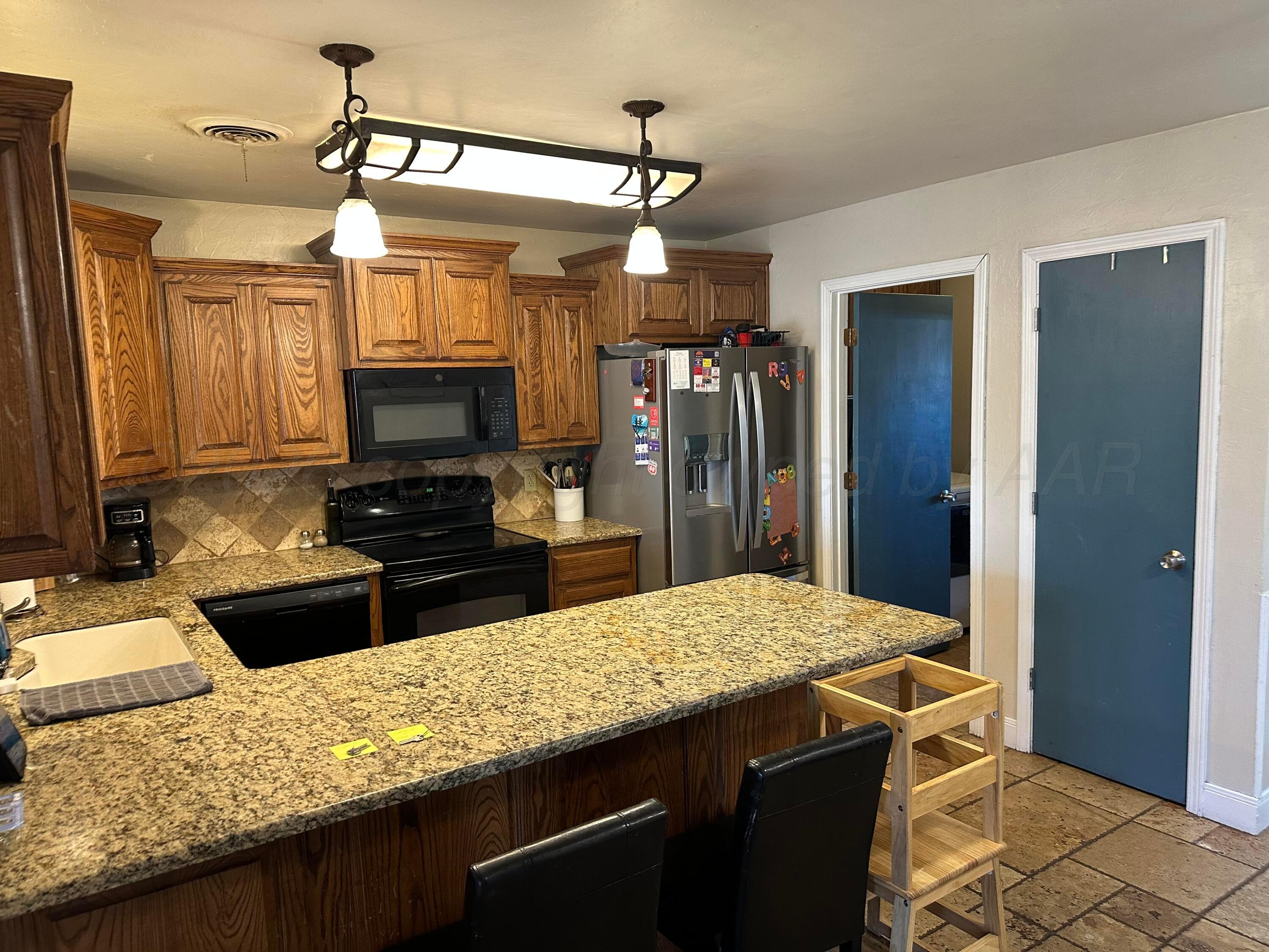 103 Somerset Street Borger, TX 79007 - Photo 8 of 23 a kitchen with granite countertop a refrigerator and a stove top oven