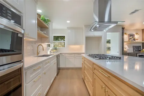 a kitchen with granite countertop a sink stainless steel appliances and cabinets