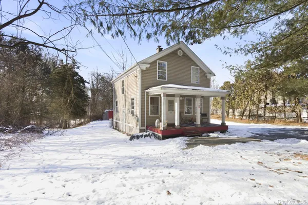 a front view of a house with a yard covered with snow and trees