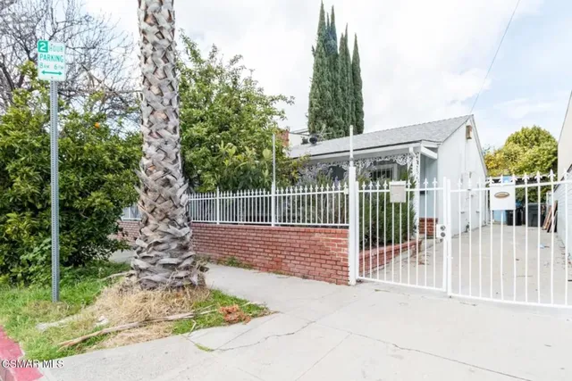 a view of a house with a small yard and wooden fence