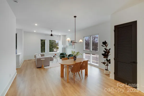 a kitchen with stainless steel appliances granite countertop a stove a sink a microwave a dining table and chairs with wooden floor